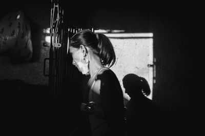 Side view of young woman standing against wall