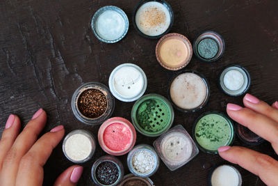 Cropped hand of woman with various jars at table