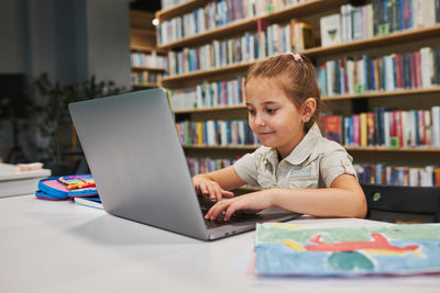 Student doing her homework using laptop in after school club at school. back to school