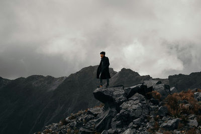 Rear view of man standing on rock against sky