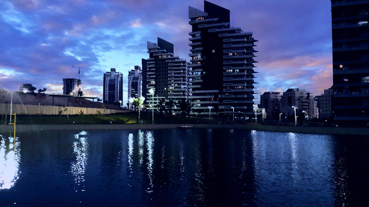 building exterior, architecture, water, built structure, waterfront, reflection, sky, city, river, cloud - sky, building, cloud, sunset, residential building, rippled, cityscape, dusk, outdoors, skyscraper, lake