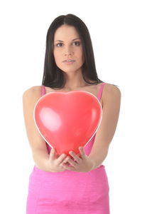 Portrait of a young woman holding heart shape over white background