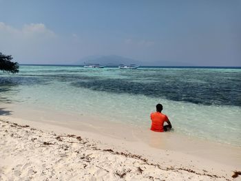 Rear view of man on beach against sky