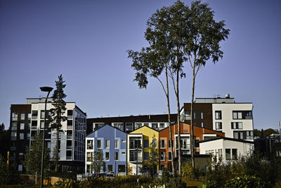 Low angle view of trees and buildings against blue sky