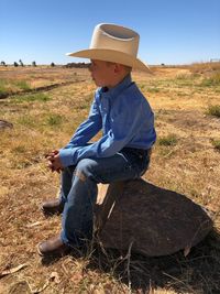 Full length of boy sitting on field