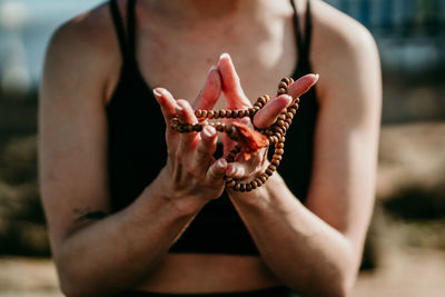 Calm crop unrecognizable female standing on the beach holding prayer beads