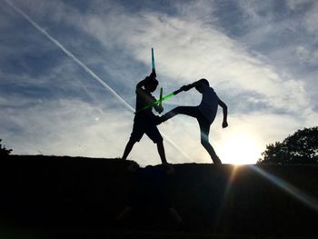 Low angle view of silhouette men against sky