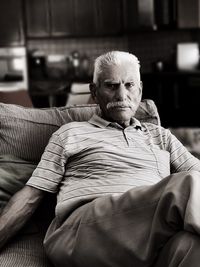 Portrait of senior man sitting on sofa at home