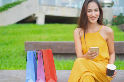 Smiling young woman using mobile phone outdoors