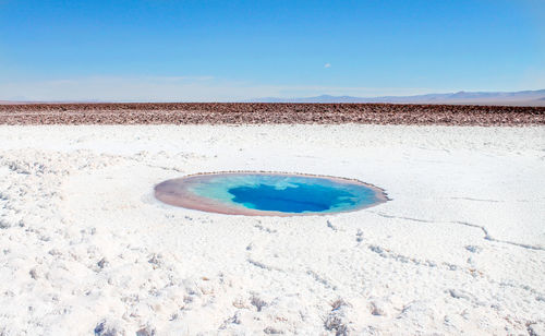 Salt desert in chile with a small lake against clear blue sky