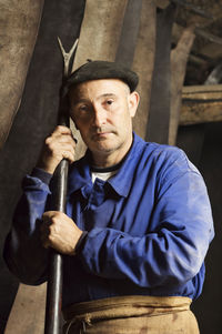 Portrait of worker holding work tool standing in tannery