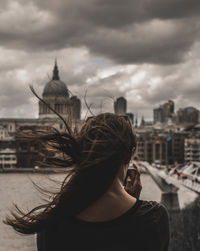 Rear view of woman photographing against tate modern in city