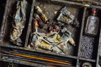 High angle view of paint tubes and brushes in abandoned box