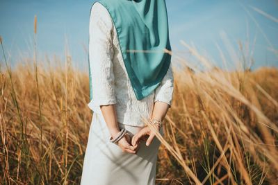 Midsection of woman standing on field against sky