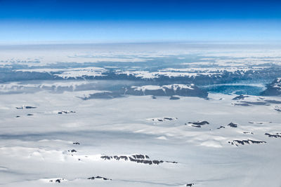 Aerial view of snowcapped mountains against blue sky