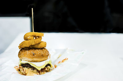 Close-up of hamburger with onion ring against black background