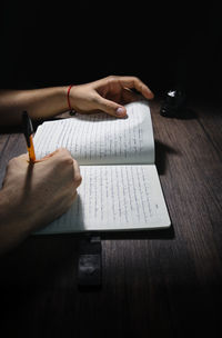 Midsection of man reading book on table