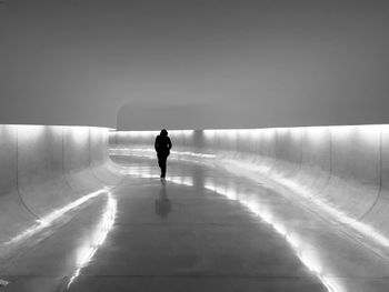 Rear view of woman walking in illuminated covered walkway