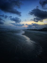 Scenic view of beach against sky at sunset