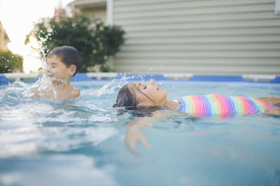 Happy siblings swimming in wading pool