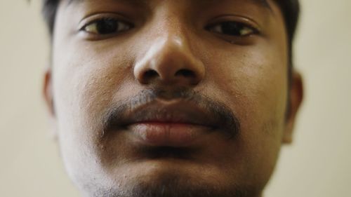 Close-up portrait of young man against wall