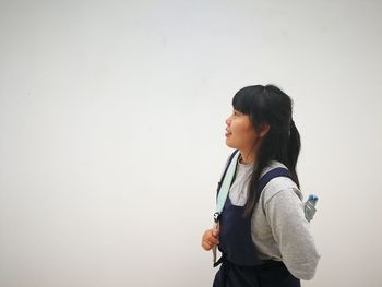 Young woman standing against white wall