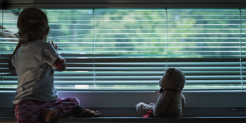 Rear view of woman looking at window