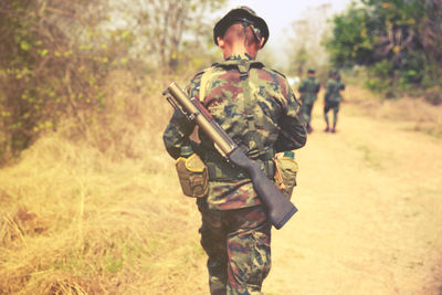 Rear view of army soldier walking in forest