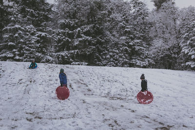 Full length of girls standing on bobsled in snow