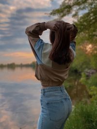 Rear view of woman standing against sky during sunset