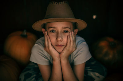 Portrait of cute boy with hands on cheek by pumpkin