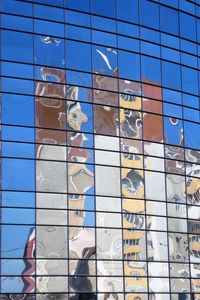 Low angle view of glass building against blue sky