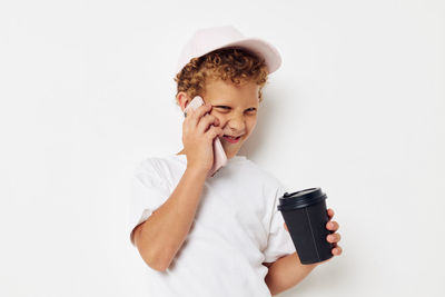 Boy talking on phone against white background