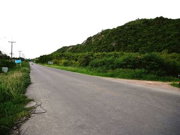 Empty road by trees against sky