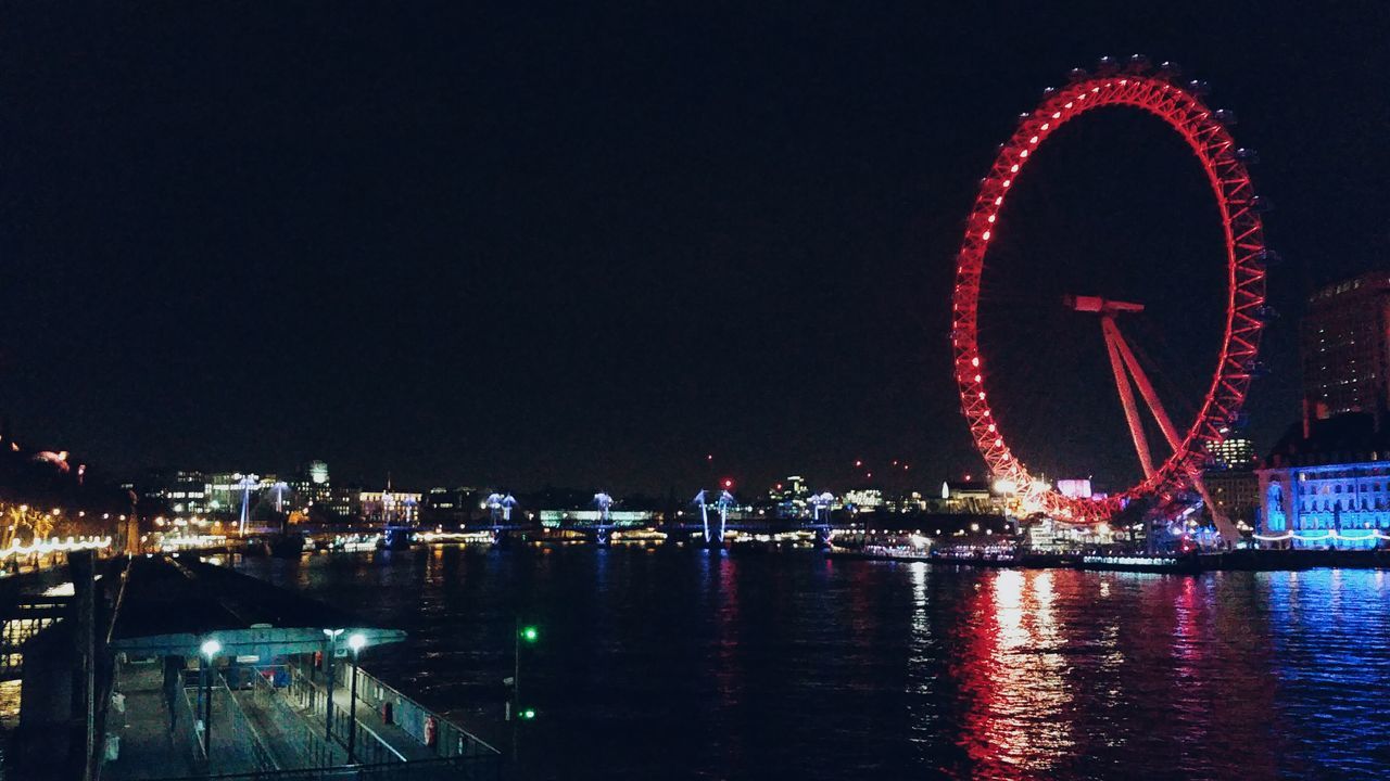 ILLUMINATED CITY BY RIVER AGAINST SKY