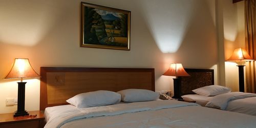 Bed and illuminated lamps in hotel room