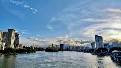 River by buildings in city against sky