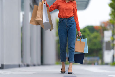 Low section of woman with umbrella on footpath