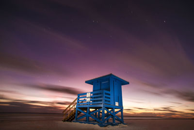 Lifeguard hut by sea against sky at night
