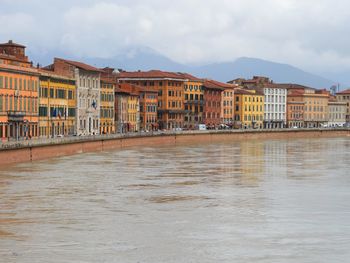 Buildings by river with city in background