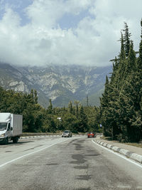 Road by mountains against sky