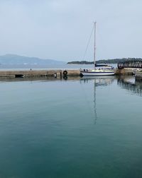 Sailboats moored on sea against sky