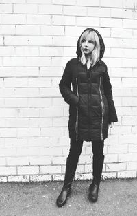 Portrait of smiling young woman standing against brick wall