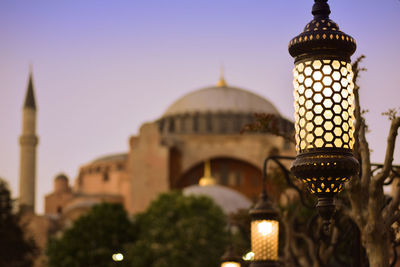 Low angle view of illuminated gas light against hagia sophia at dusk