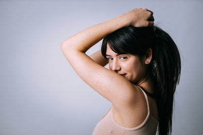 Portrait of young woman standing against gray background