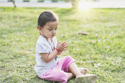 Side view of young woman sitting on field