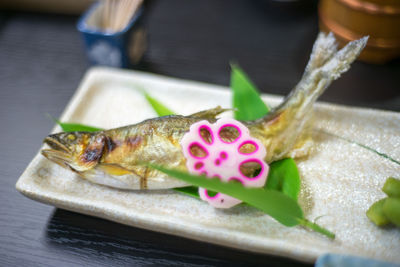 High angle view of grilled fish on served in plate on restaurant table