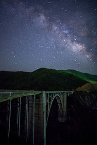 Scenic view of bridge over mountains against sky at night