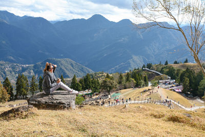 Man sitting on land against mountains