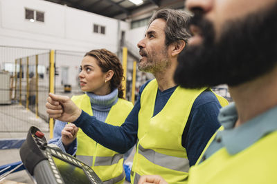 Engineer holding control panel working with colleagues in factory